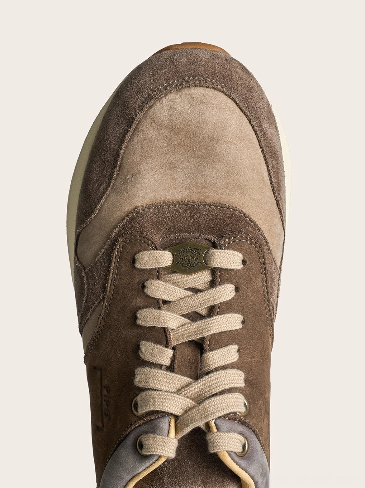 Top view of brown retro trail runner sneakers showing two-tone suede panels, rounded toes, and flat cotton laces