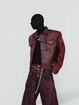 Washed burgundy grommet collar cropped moto jacket in left three-quarter view styled with matching wide-leg pants and silver chain belt