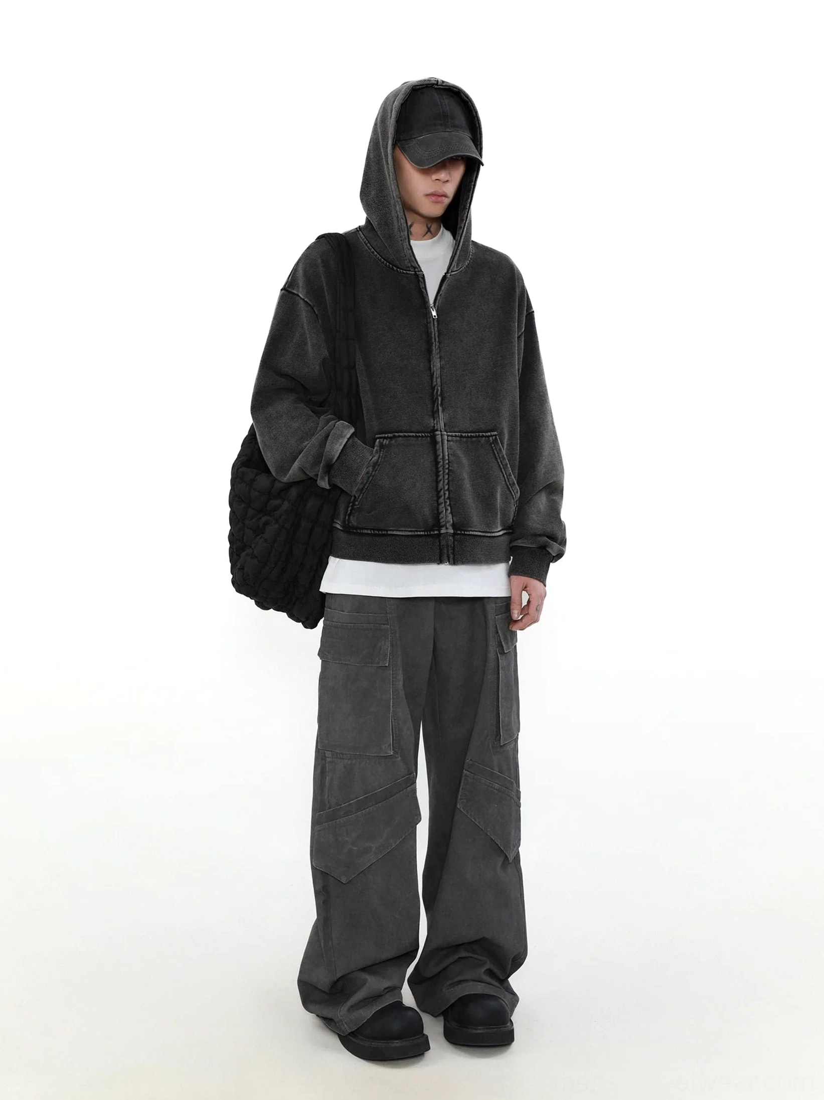 Washed charcoal black zip-up hoodie left side view styled with wide-leg cargo pants for a relaxed urban streetwear outfit