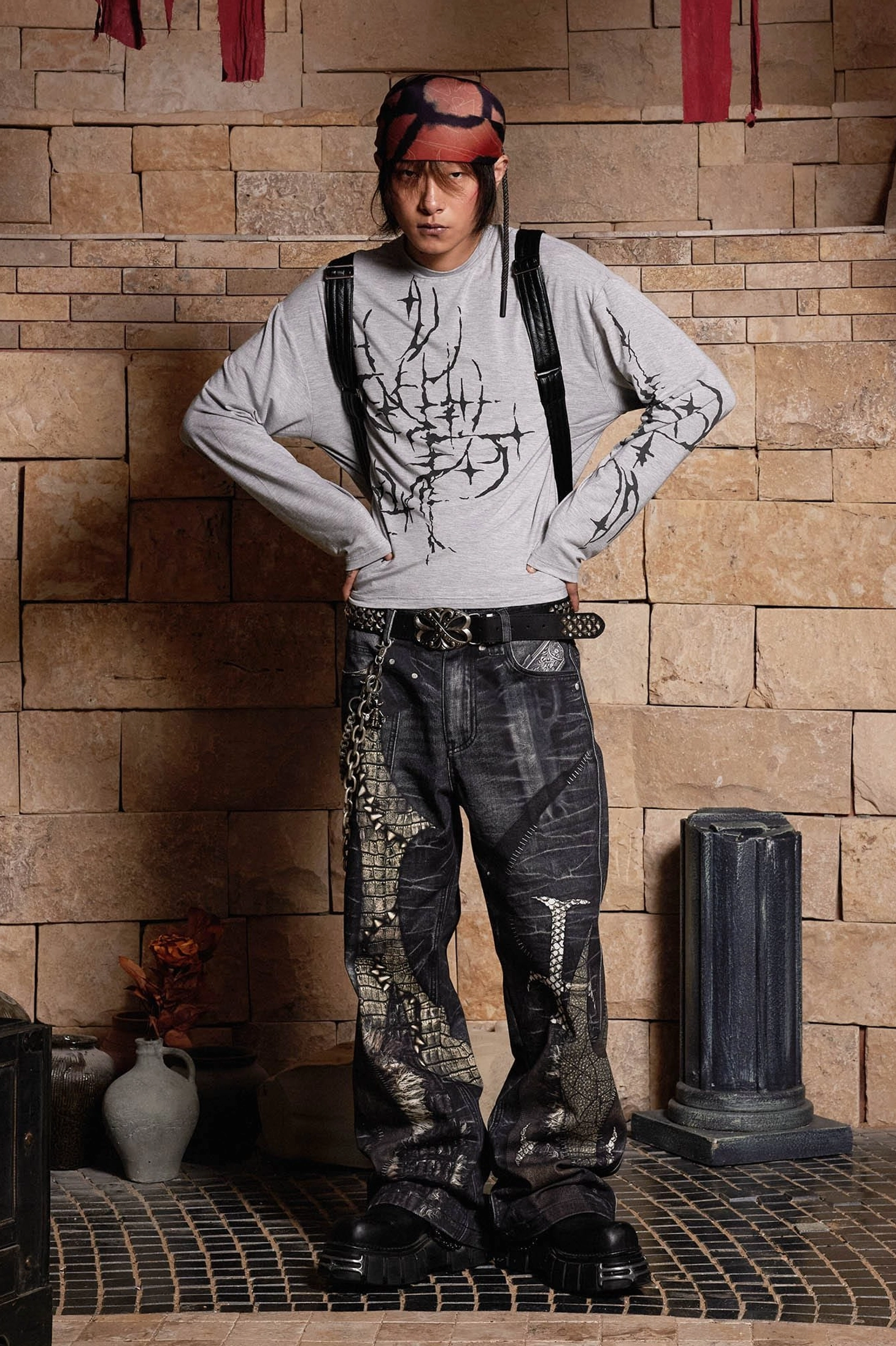 Front styling view of washed charcoal gothic wide-leg jeans with matching leg graphics, metal chain decorations, and relaxed baggy fit