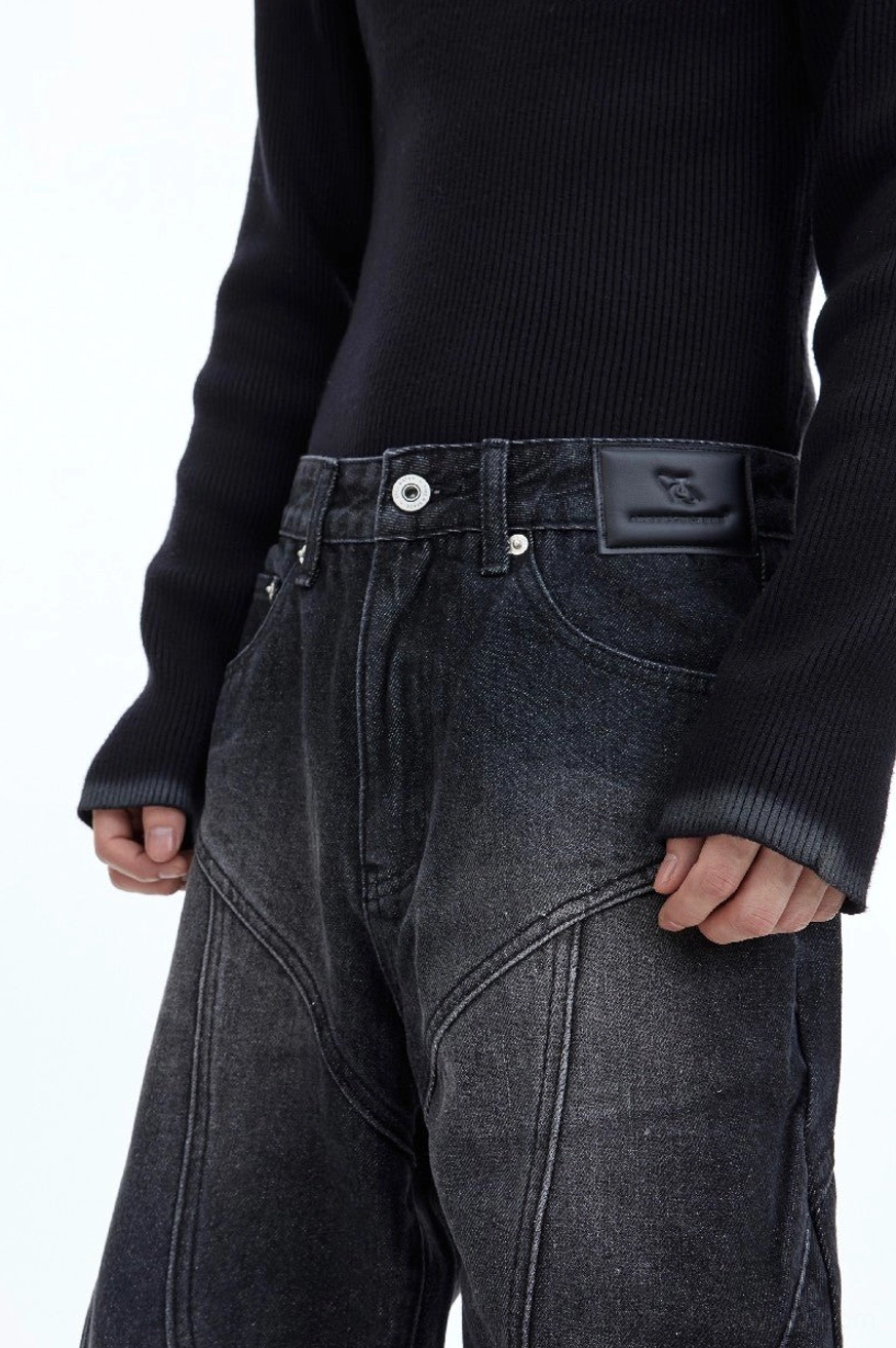 Close-up detail of washed charcoal streetwear jeans with metal button belt loops leather waist patch and contrast panel stitching