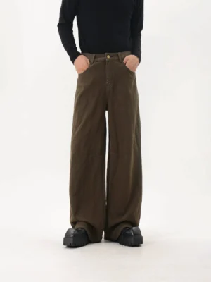 Dark coffee brown washed wide-leg pants shown from the front with curved pockets, button and zip fastening, panel seam details, and chunky platform boots in a minimalist streetwear studio outfit