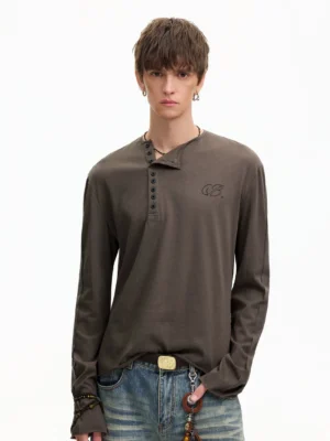 Front full-body view of a male model wearing an espresso brown washed cotton Henley long sleeve tee with notched neckline, button placket, and embroidered chest detail