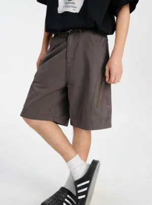 Angled front side view of washed dark gray hip hop cargo shorts with zipper pocket and oversized streetwear silhouette