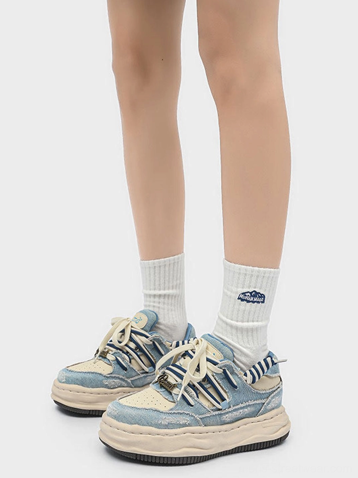 Front on-foot view of washed denim dual-lace chunky streetwear sneakers with coordinated white logo socks
