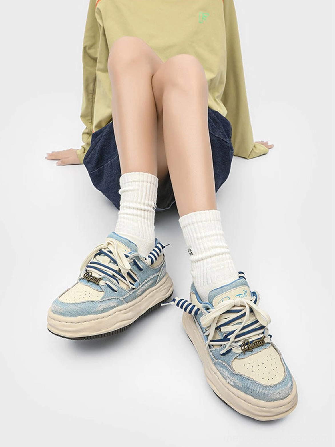 Pair of washed denim dual-lace chunky streetwear sneakers worn with white socks in front view
