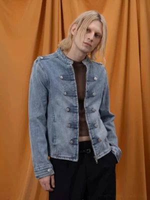 Male model wearing washed denim military epaulette cropped zip jacket with silver button front in orange studio
