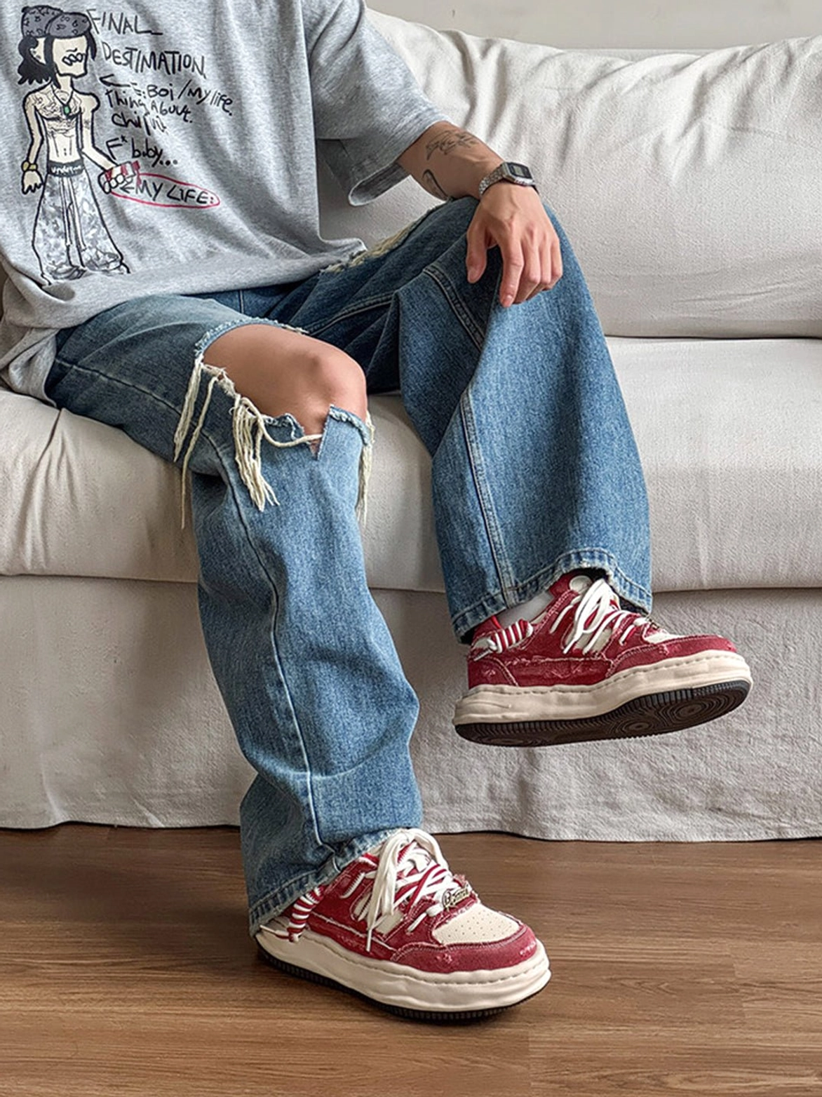Side view of washed denim streetwear sneakers worn with ripped blue jeans and a graphic tee in a relaxed indoor setting