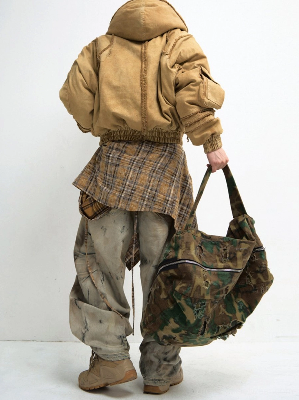 Wide-leg distressed cargo jeans back full-body streetwear outfit with khaki jacket plaid shirt and camouflage tote