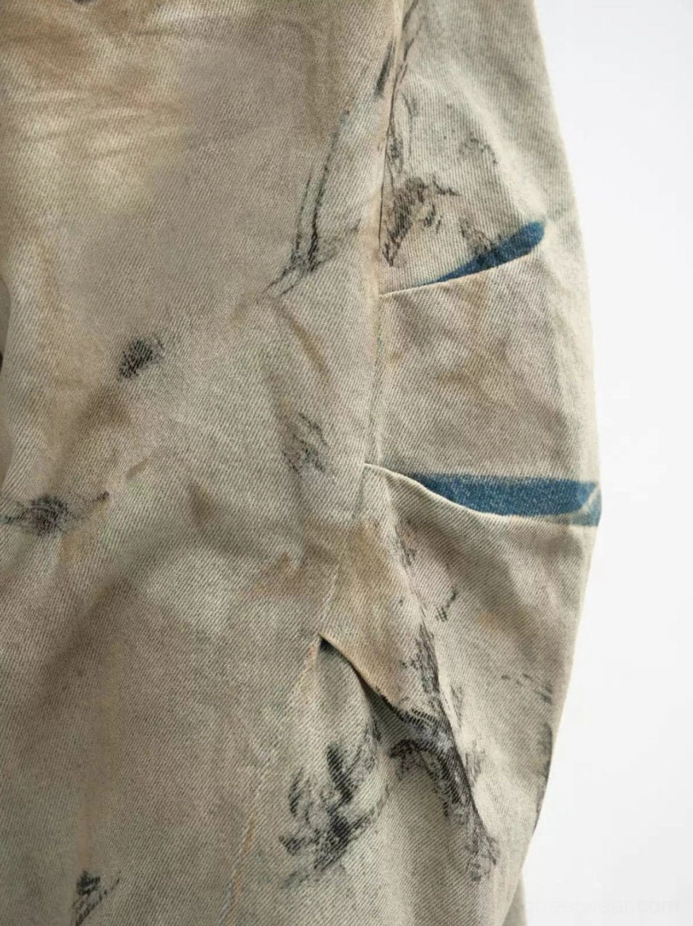 Close-up of faded distressed denim cargo pocket with visible utility stitching and indigo inner fabric