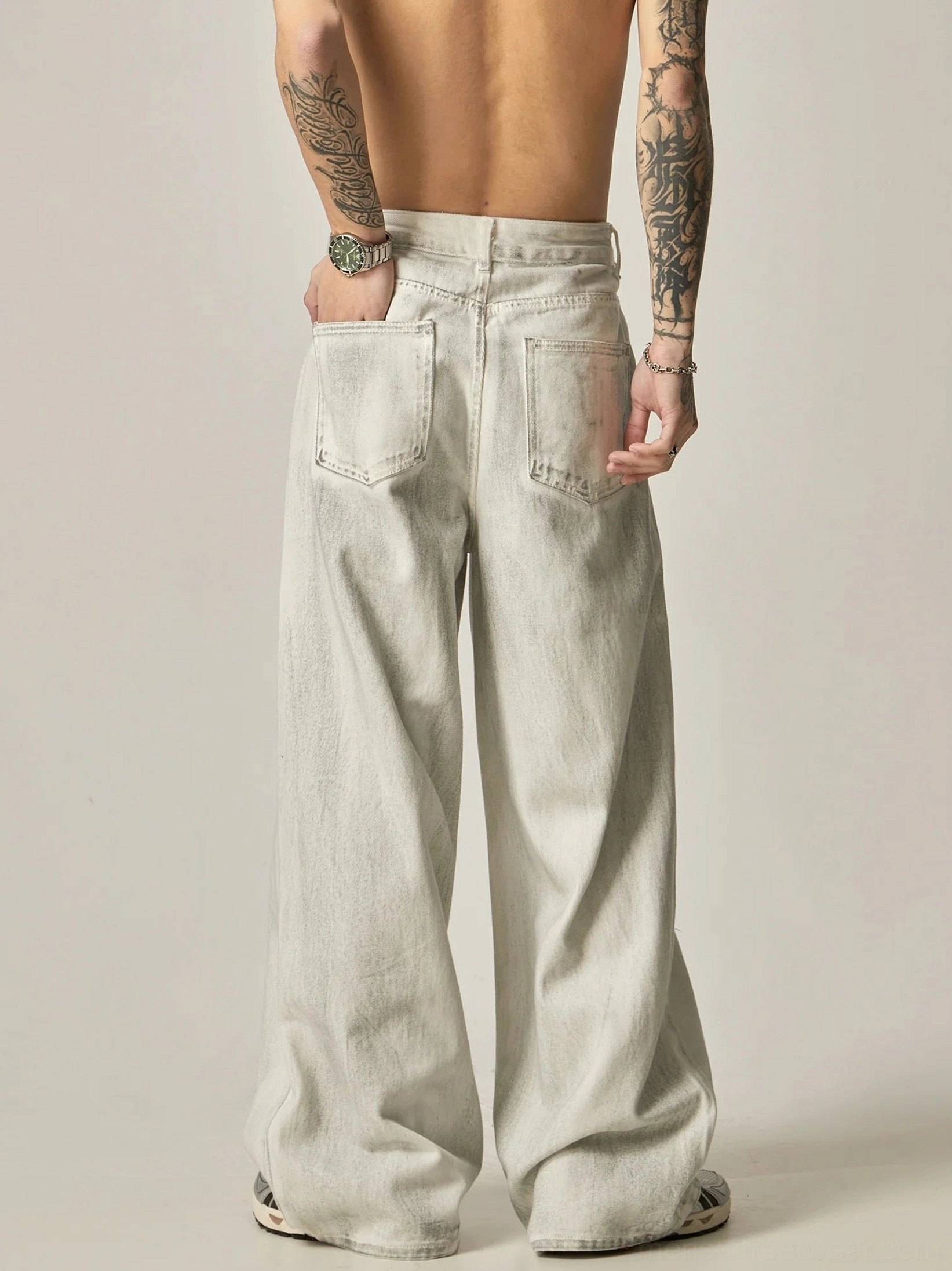 Back view of off-white washed wide-leg jeans showing rear patch pockets and relaxed streetwear denim silhouette