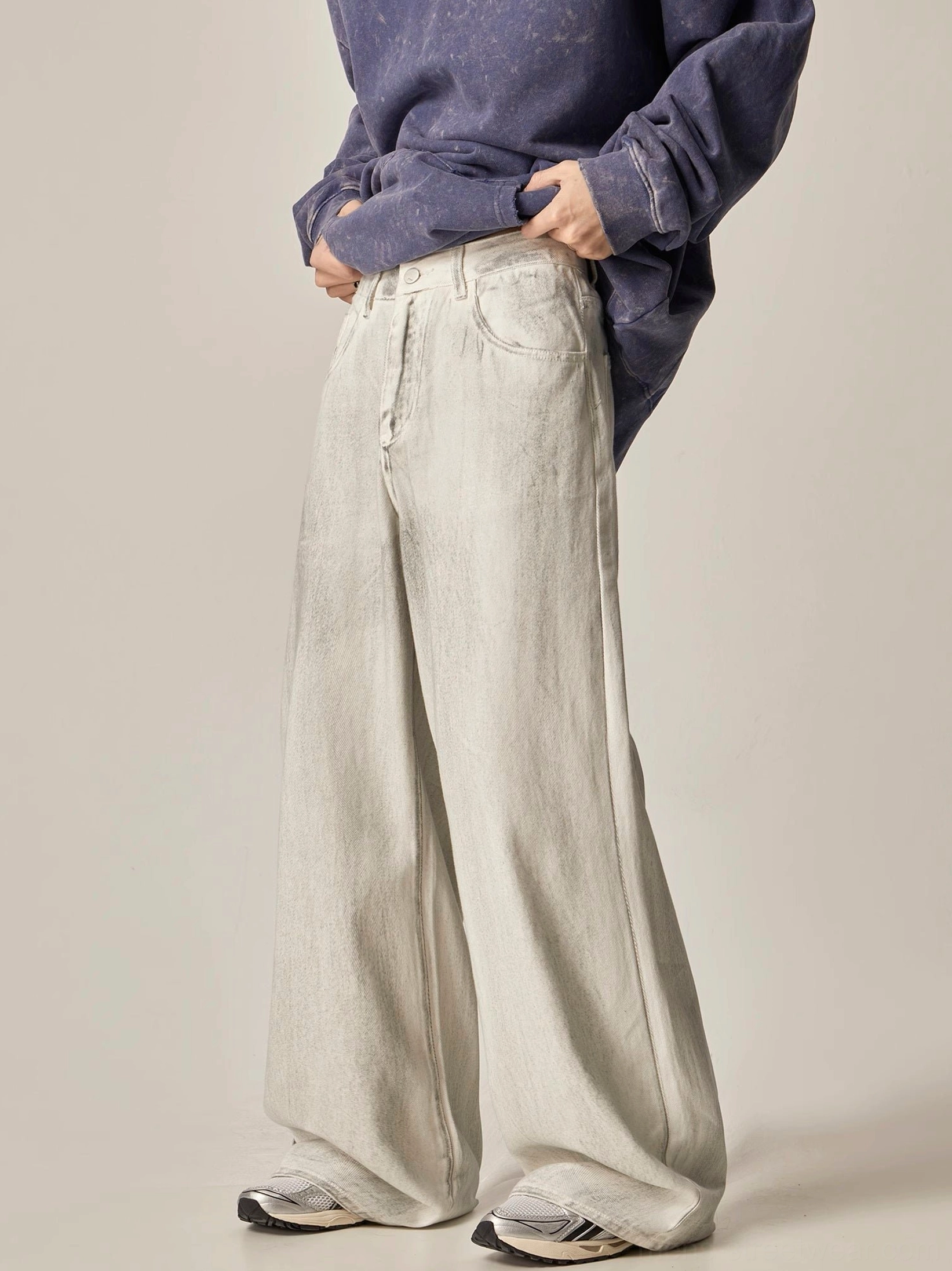 Three-quarter front view of washed off-white wide-leg denim jeans with natural waist and front fly closure