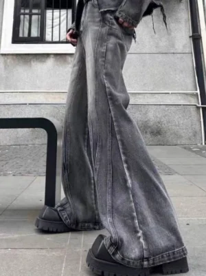 Side view of washed gray black flared denim jeans showing the wide hem, vintage fade, and relaxed streetwear silhouette