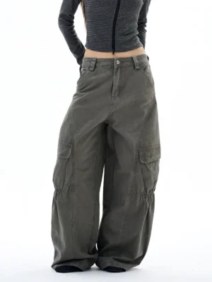 Front three-quarter view of washed gray-green wide-leg cargo pants with oversized utility pockets and gathered knee details