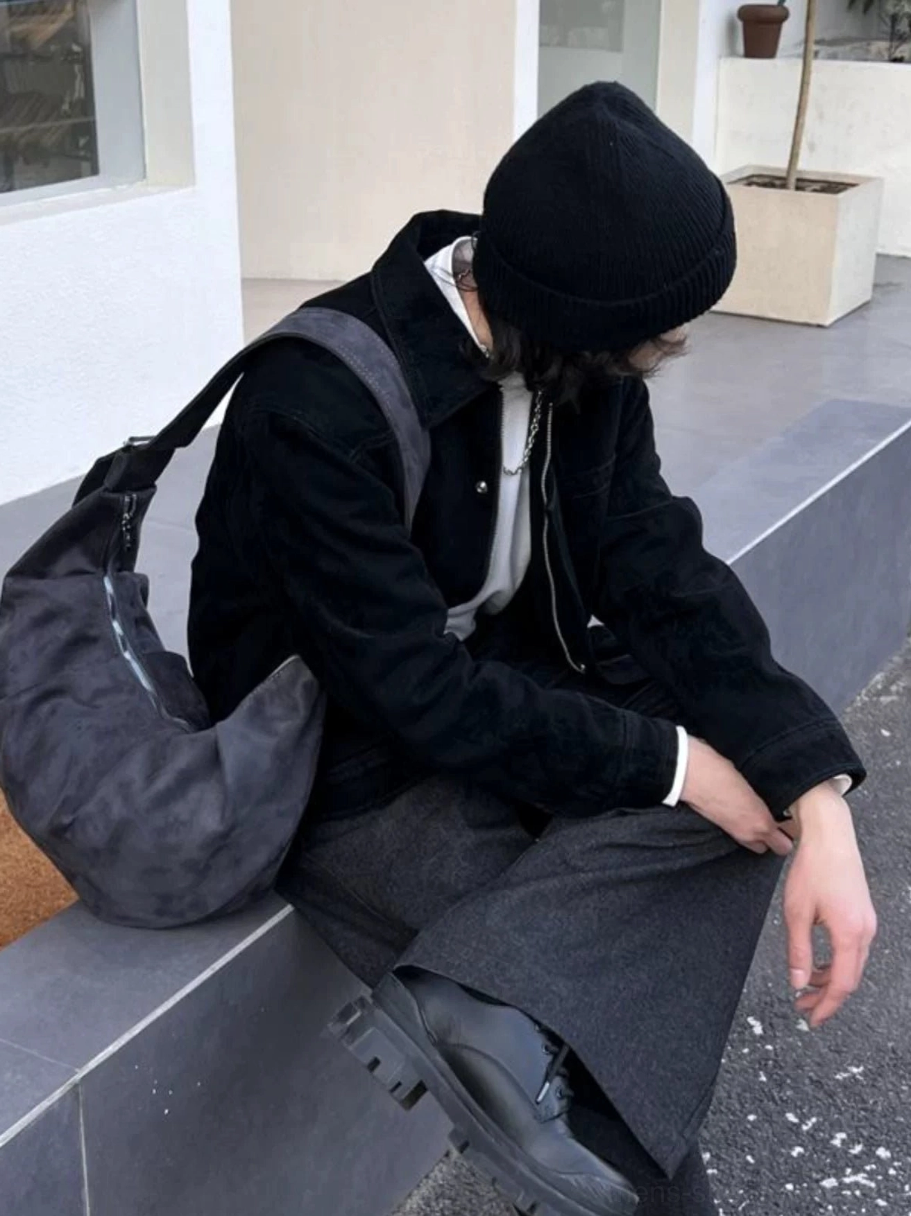Washed gray slouchy hobo shoulder bag worn while seated showing soft curved silhouette and wide strap
