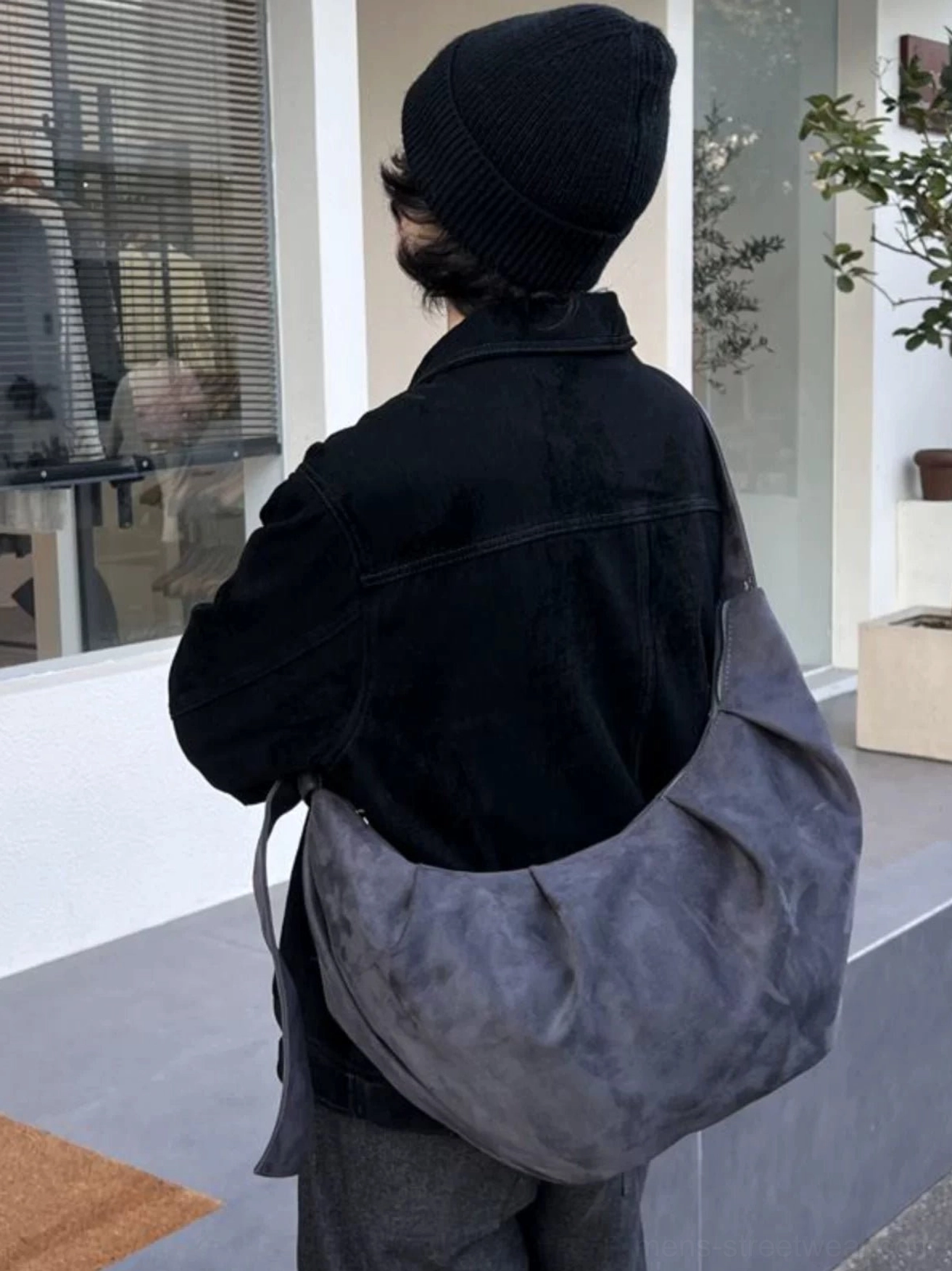Washed gray suede-look crescent hobo shoulder bag worn with dark minimalist streetwear outside boutique