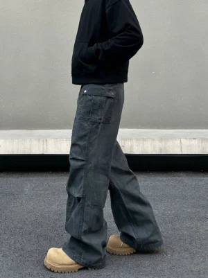 Side view of gray washed wide-leg cargo pants with flap utility pocket and articulated seam panels