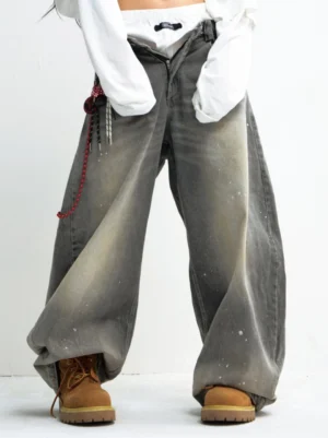 Washed grey paint-splatter wide leg jeans styled with a cropped white top, work boots, and layered streetwear accessories