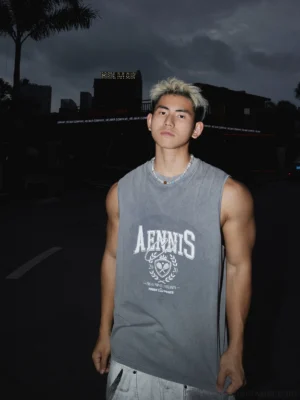 Front view of a washed grey sleeveless tennis graphic muscle tee with oversized crew neck and varsity sports print styled in urban streetwear