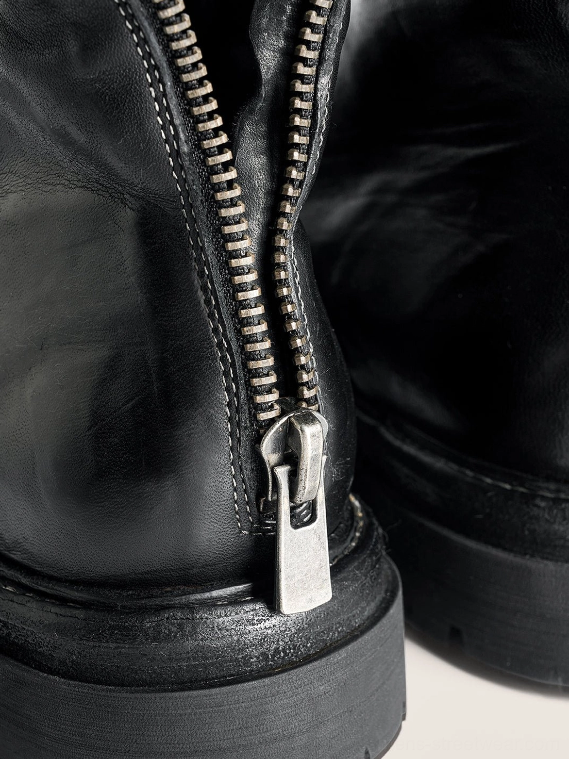 Close-up of heavy-duty metal rear zipper and stitched black washed horsehide leather on combat boot