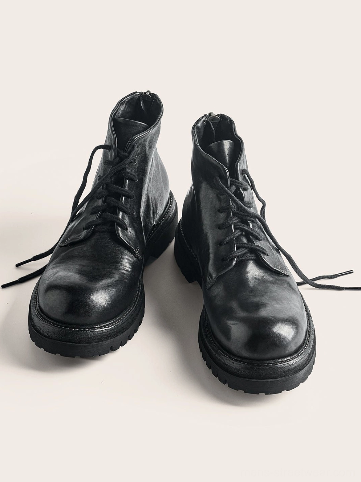 Pair of black washed horsehide rear-zip combat boots showing rounded toes front laces and lugged rubber soles
