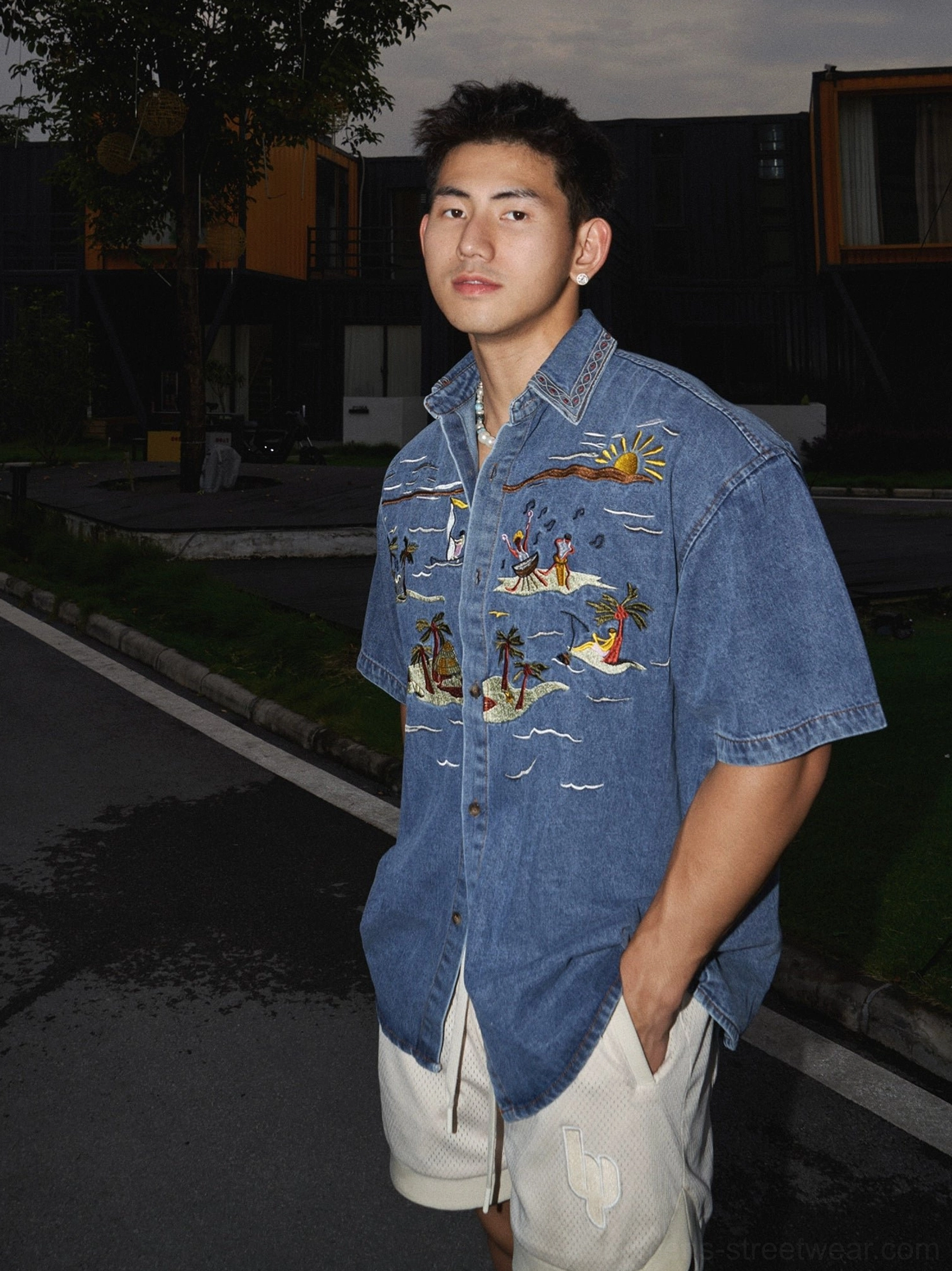 Three quarter view of washed indigo denim button up shirt with full front palm tree and sunset embroidery