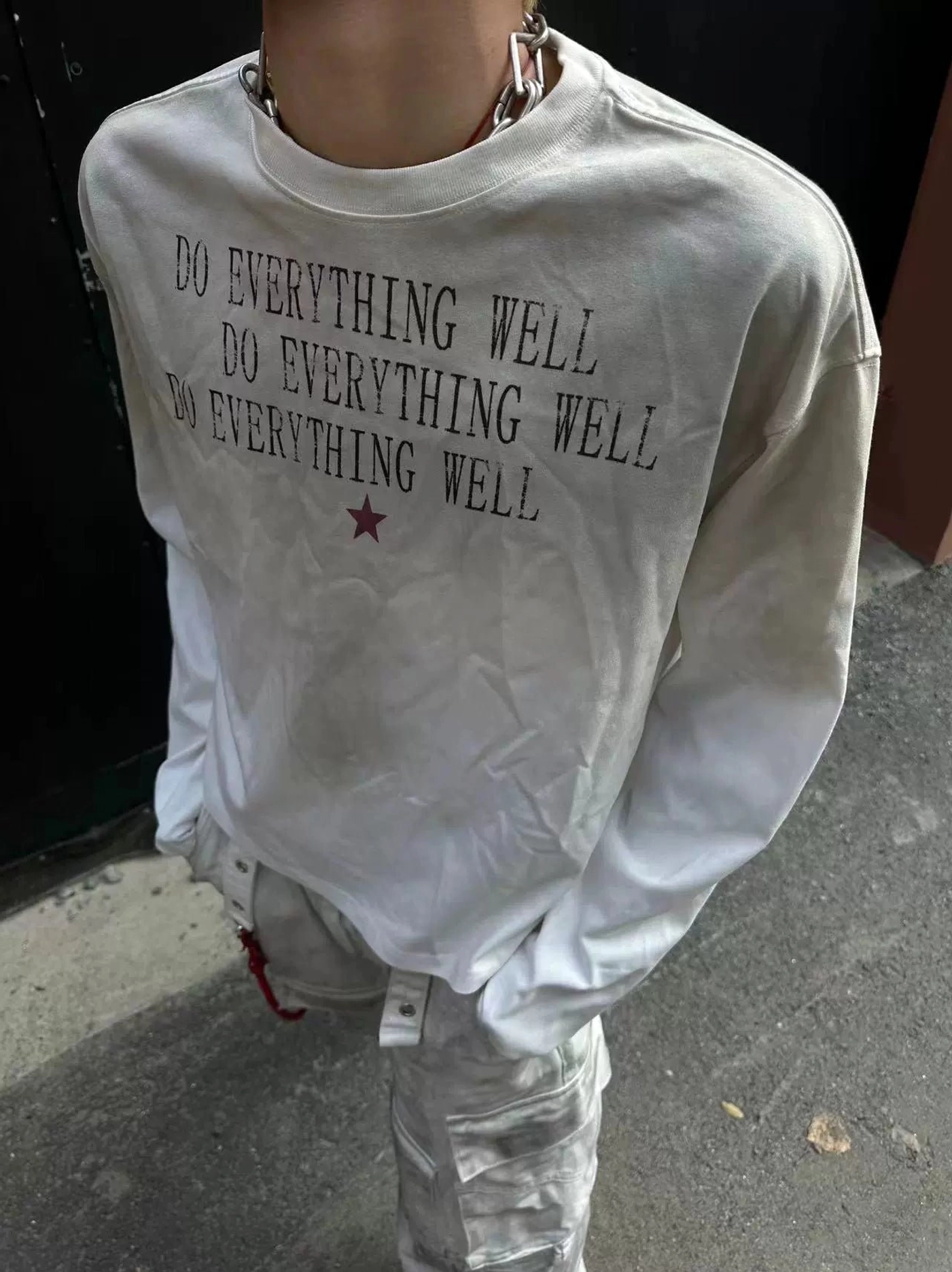 Close-up of washed ivory slogan long sleeve tee with distressed do-everything-well chest print and red star