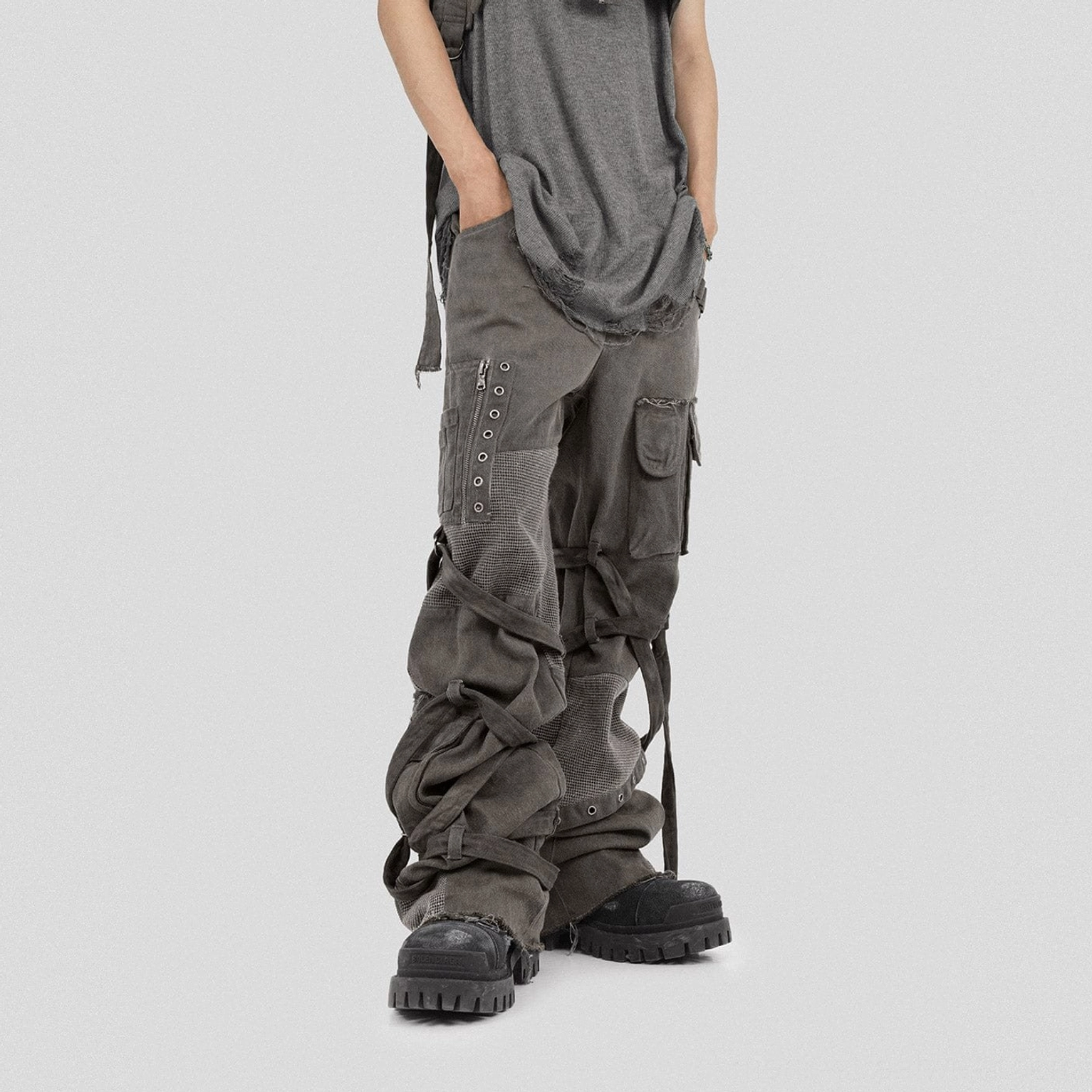 Side front view of washed dark grey tactical cargo pants with metal eyelet straps and oversized utility pockets