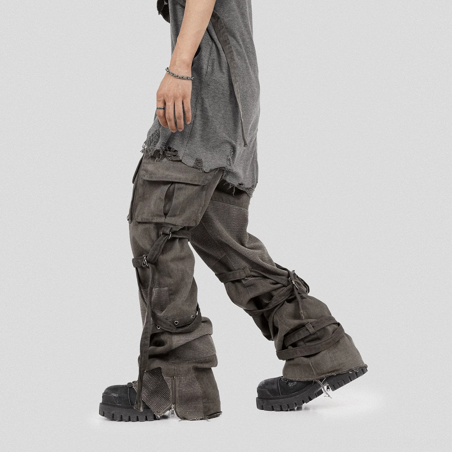 Rear side view of washed mesh tactical cargo pants with flap pockets leg straps and frayed wide-leg hems