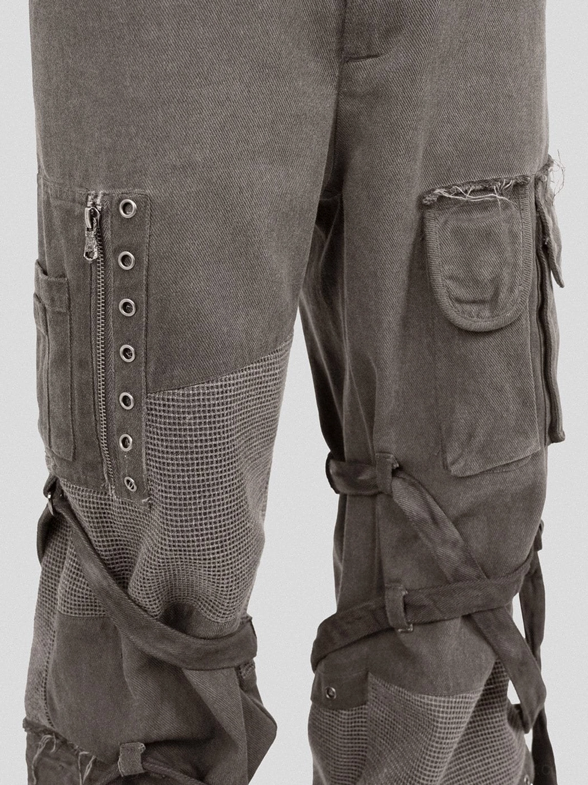 Close-up side leg detail of washed mesh tactical cargo pants with zipper metal eyelets utility pocket and fastening straps