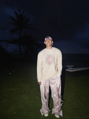 Full body view of cream yellow washed oversized graphic long sleeve tee styled with wide leg lace-up pants for Seoul streetwear