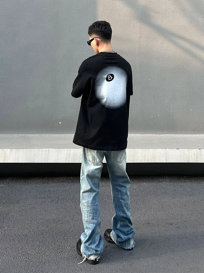 Rear full-body view of loose washed distressed wide-leg jeans styled with a black graphic shirt and leather shoes