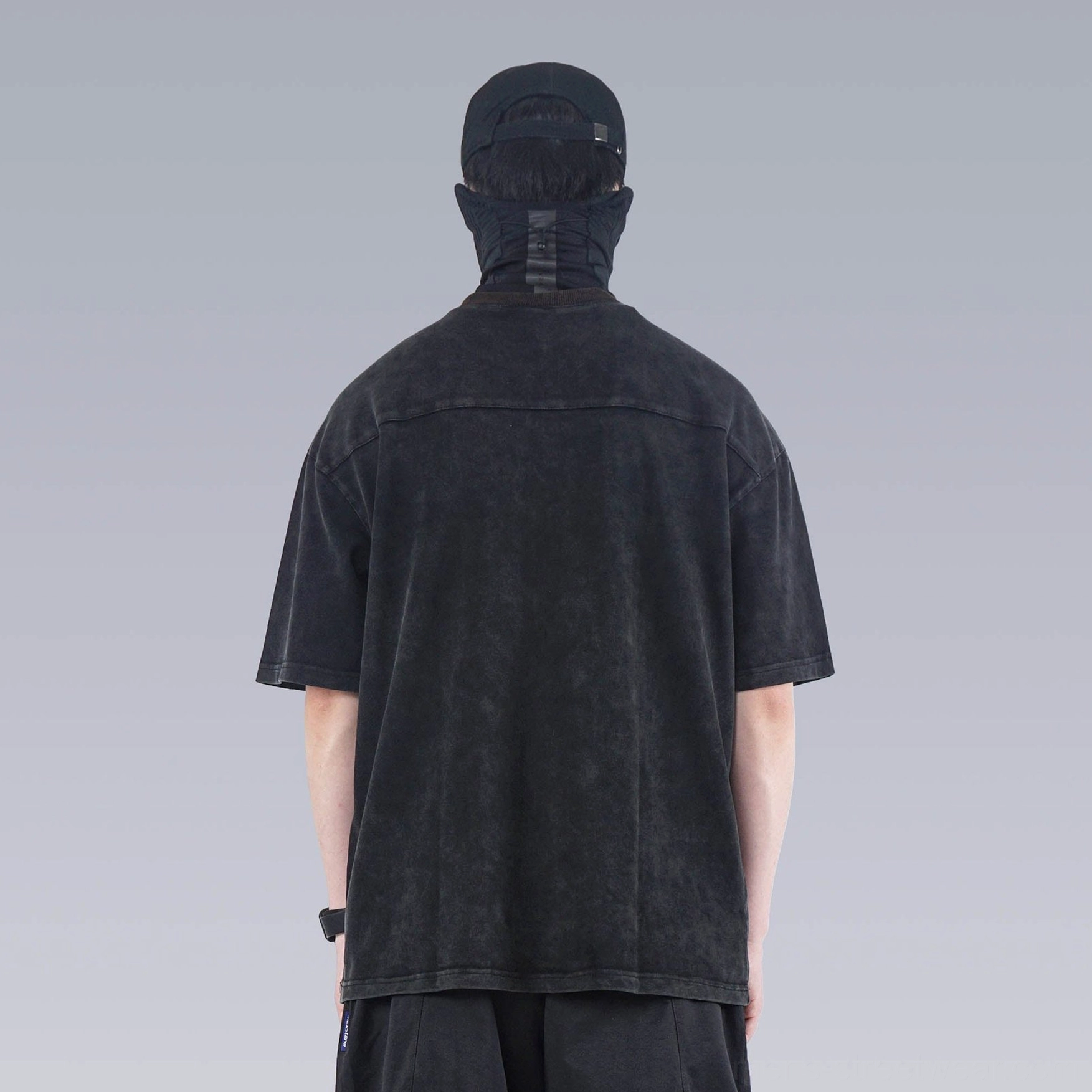 Back view of faded black washed technical oversized T-shirt with clean back panel and relaxed hemline