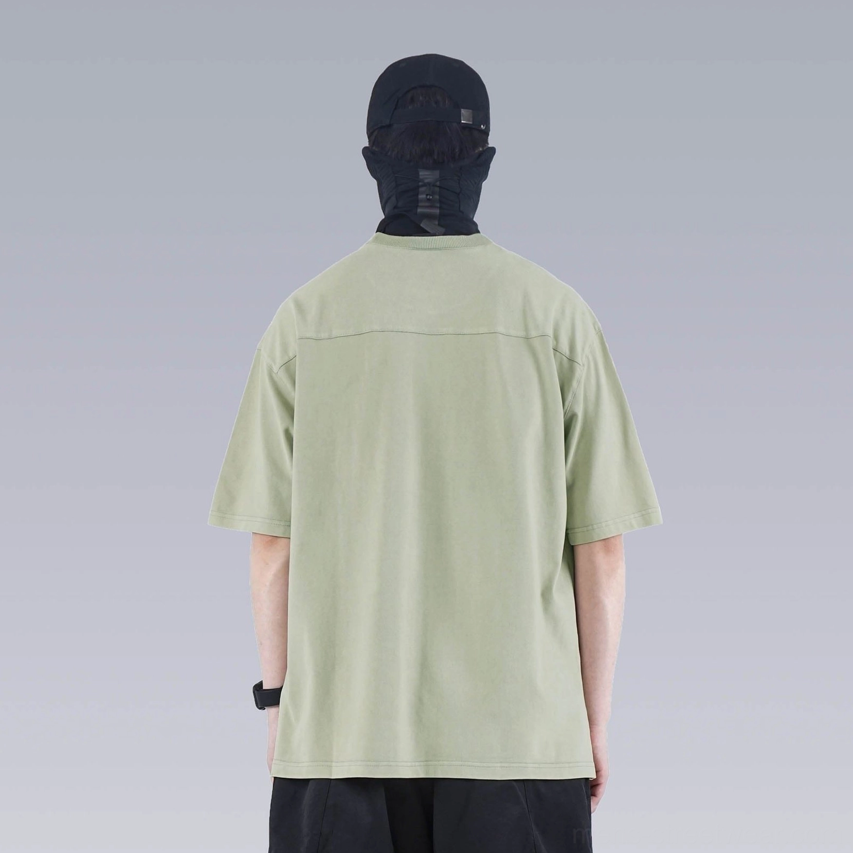 Back view of sage green washed technical oversized T-shirt with clean seam detailing and loose silhouette
