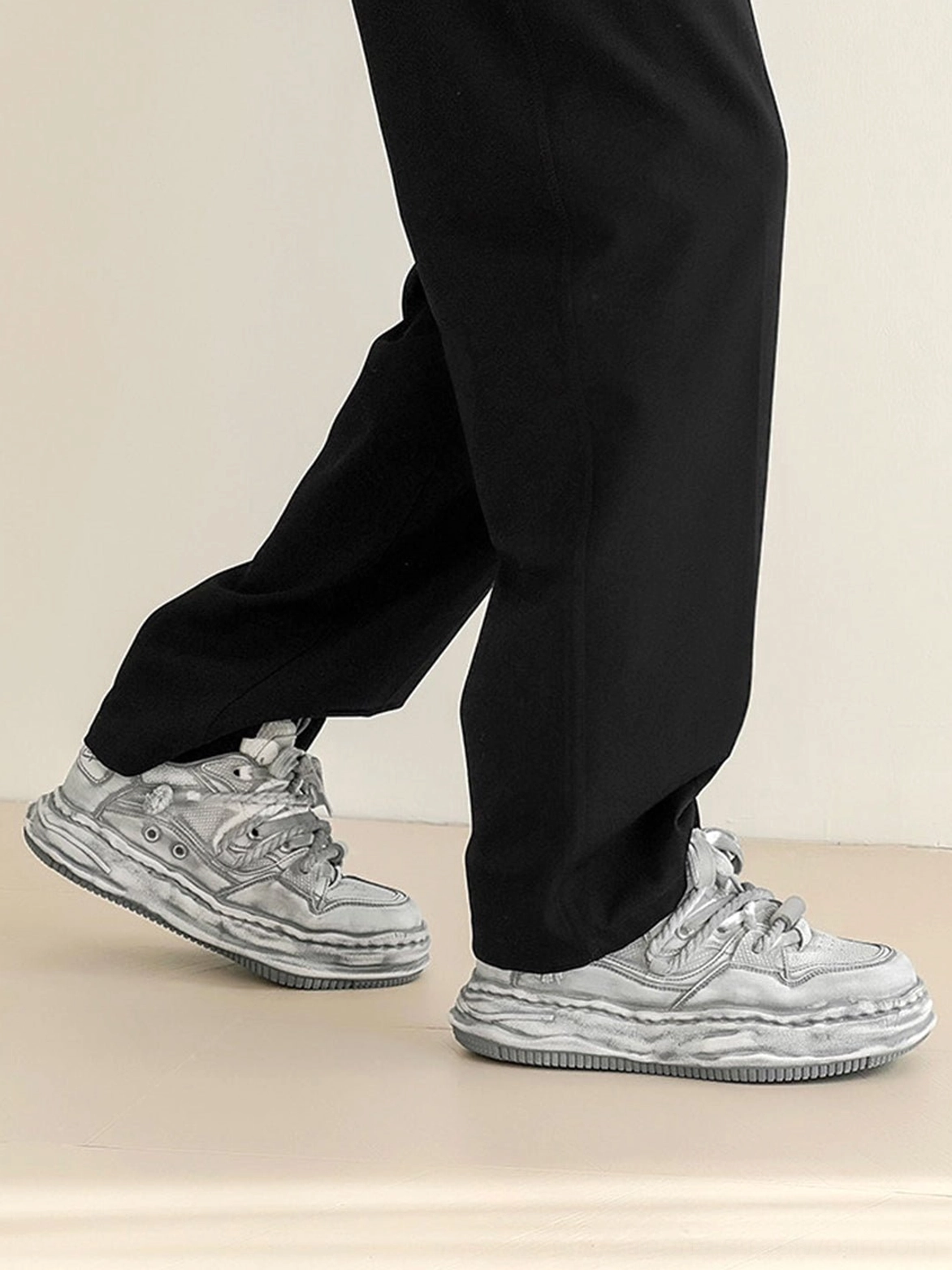 Rear side view of washed wavy platform sneakers worn with straight black suit pants highlighting the sculpted wave sole