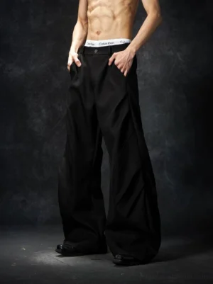 Black wave contour wide-leg trousers on a male model featuring a tailored waistband, side pockets, and relaxed oversized streetwear fit