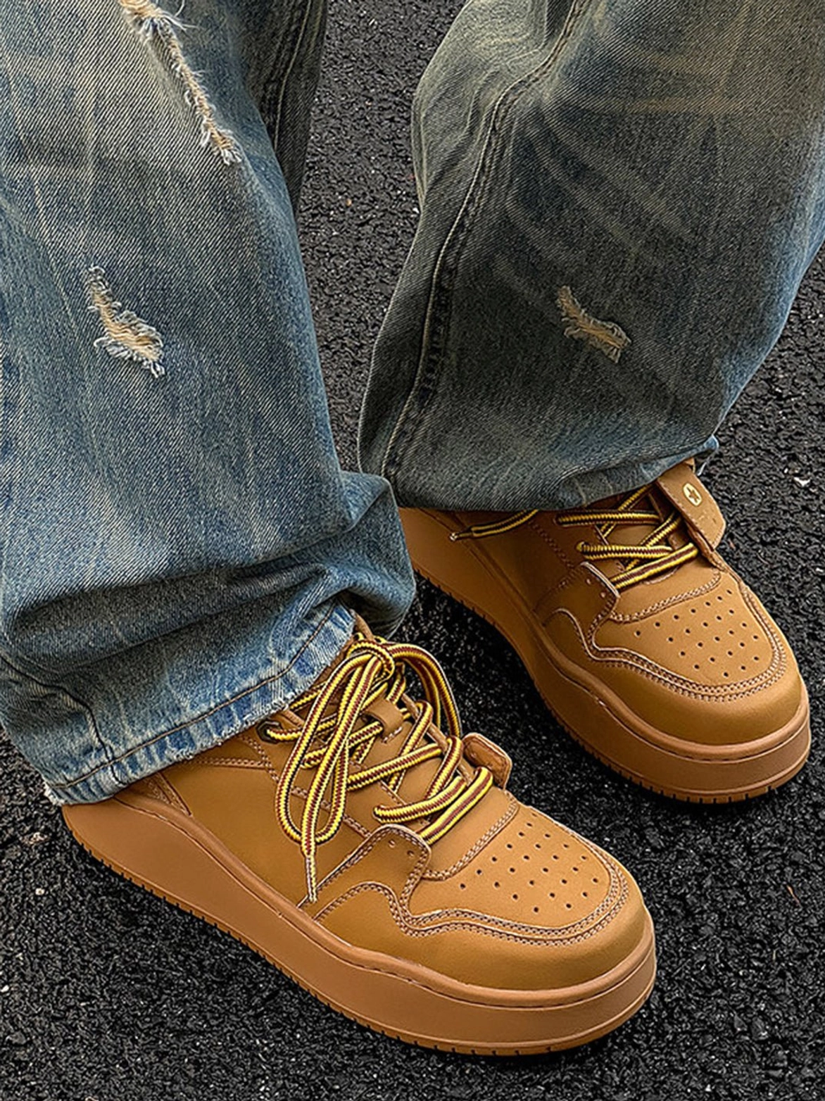 Wheat brown chunky platform sneakers worn with ripped denim jeans in a low ground-level three-quarter view