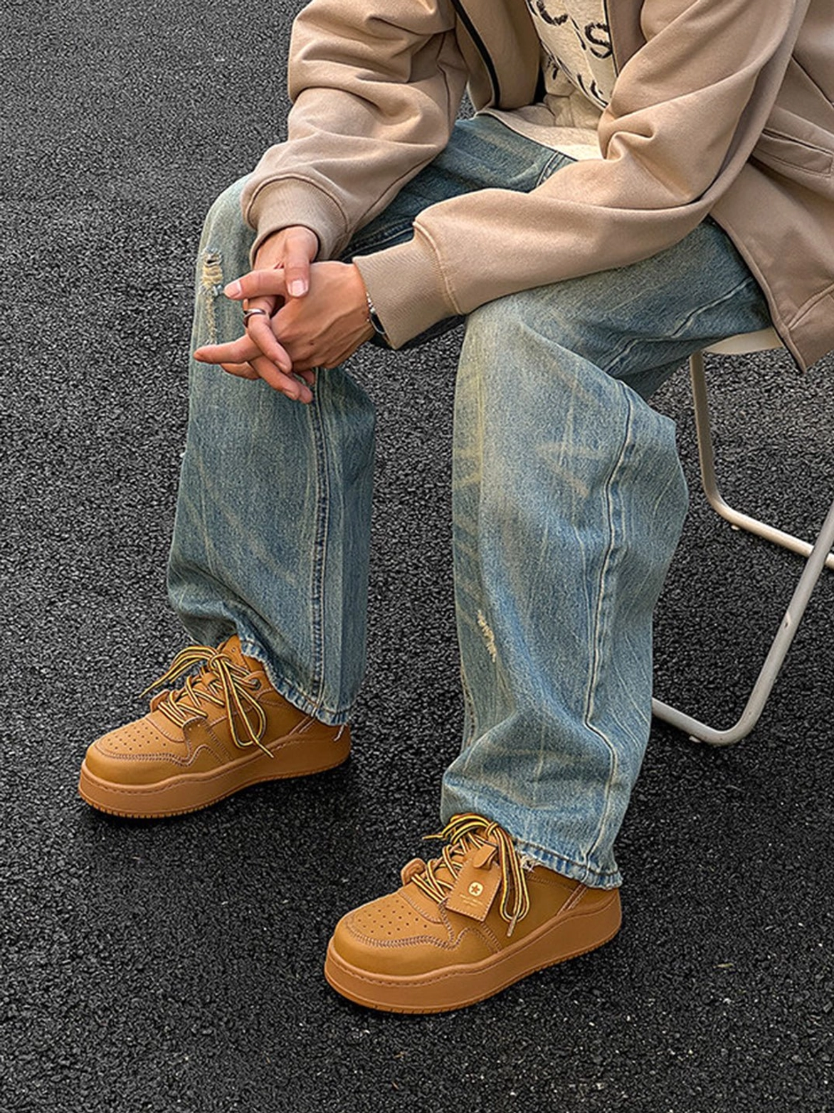 Wheat brown platform sneakers styled with baggy ripped jeans in a relaxed outdoor Korean streetwear look
