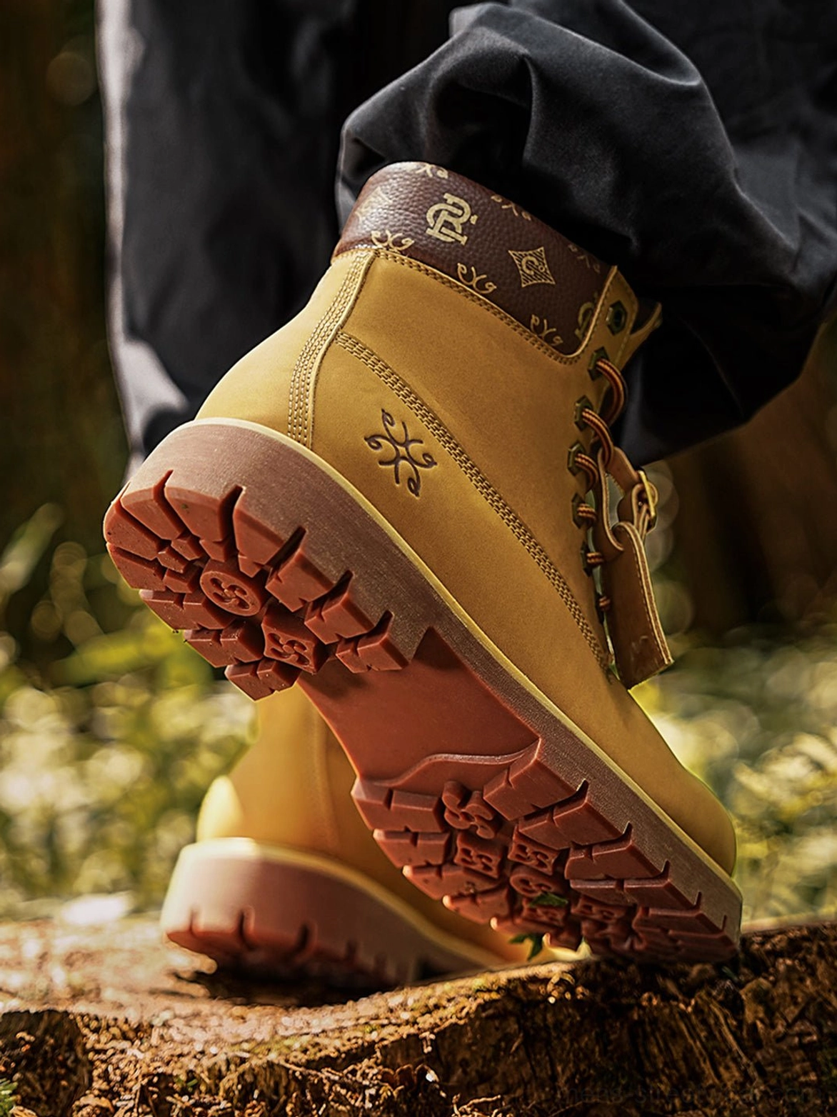 Low-angle close-up of wheat lug sole work boots showing the deep rubber tread, embossed snowflake detail, and contrast printed collar