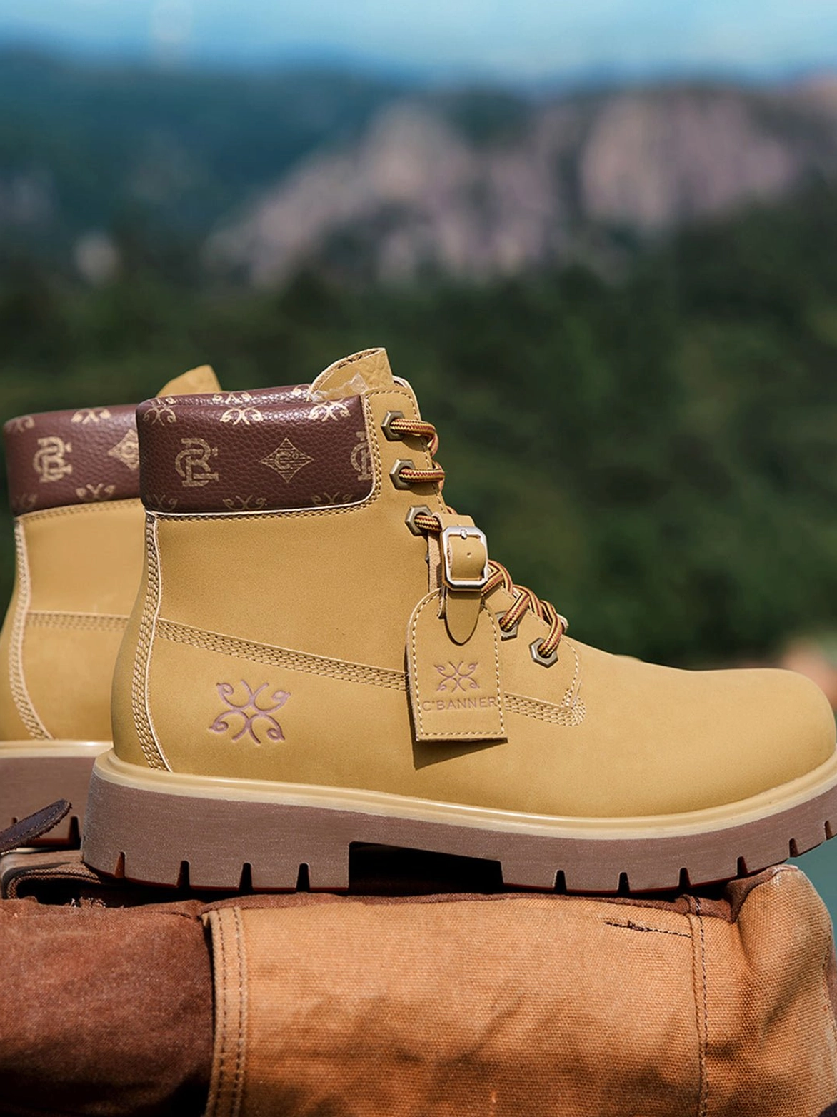 Wheat mid-top work boots displayed outdoors with a brown printed collar, embossed snowflake detail, metal eyelets, and thick lug sole