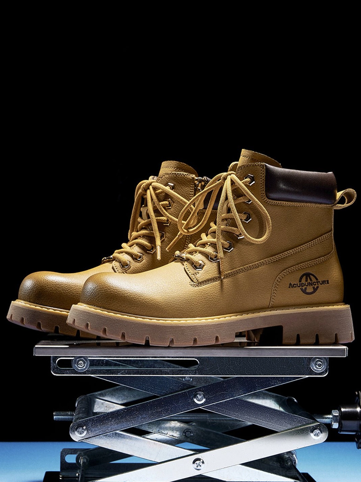 Pair of wheat yellow work ankle boots displayed on a metal platform with thick contrast lug soles