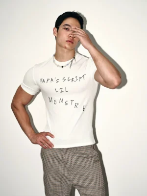 White Acubi streetwear script graphic fitted T-shirt shown from a three-quarter front view with handwritten chest lettering and checked trousers