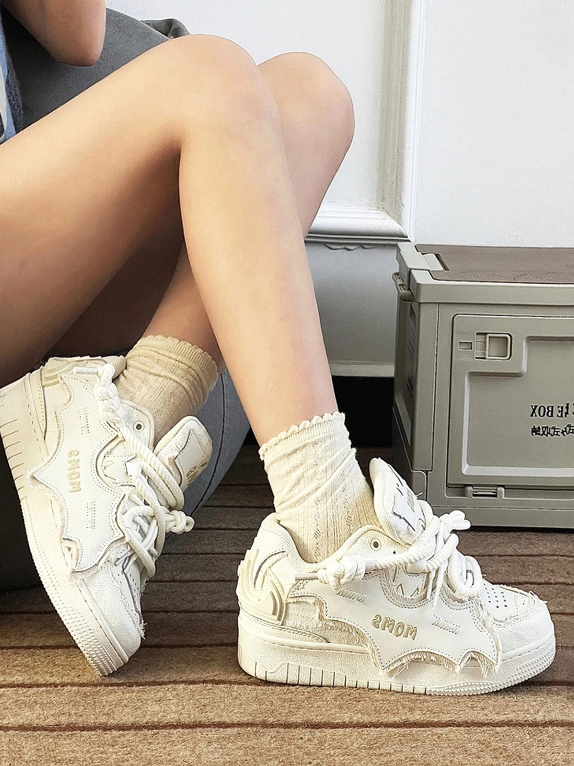 White bat-style platform sneakers worn with ruffled beige socks, featuring distressed leather texture, sculpted bat-wing vamp overlays, and avant-garde Korean streetwear styling