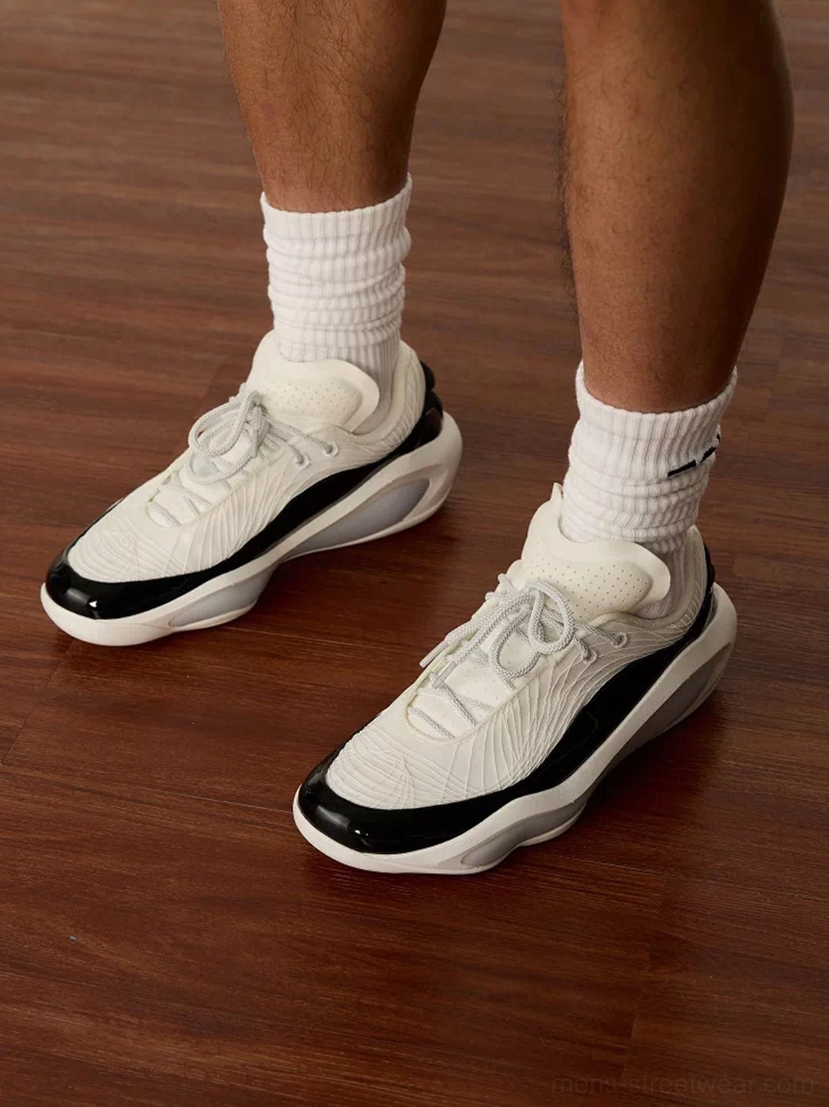 Front view of white and black leather basketball sneakers worn with white crew socks showing lace-up design