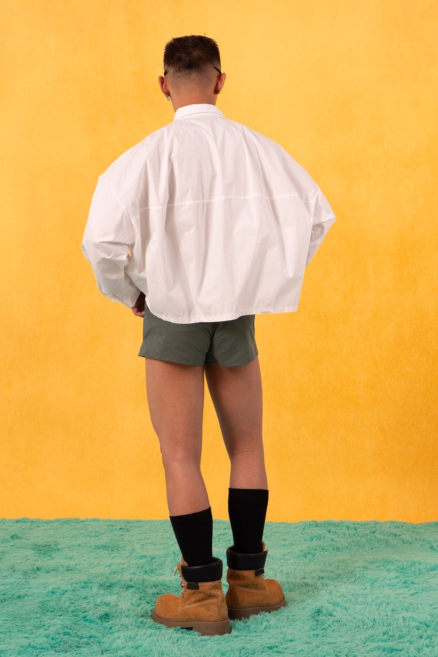 Back view of a clean white boxy cropped poplin shirt styled with dark green shorts for modern streetwear