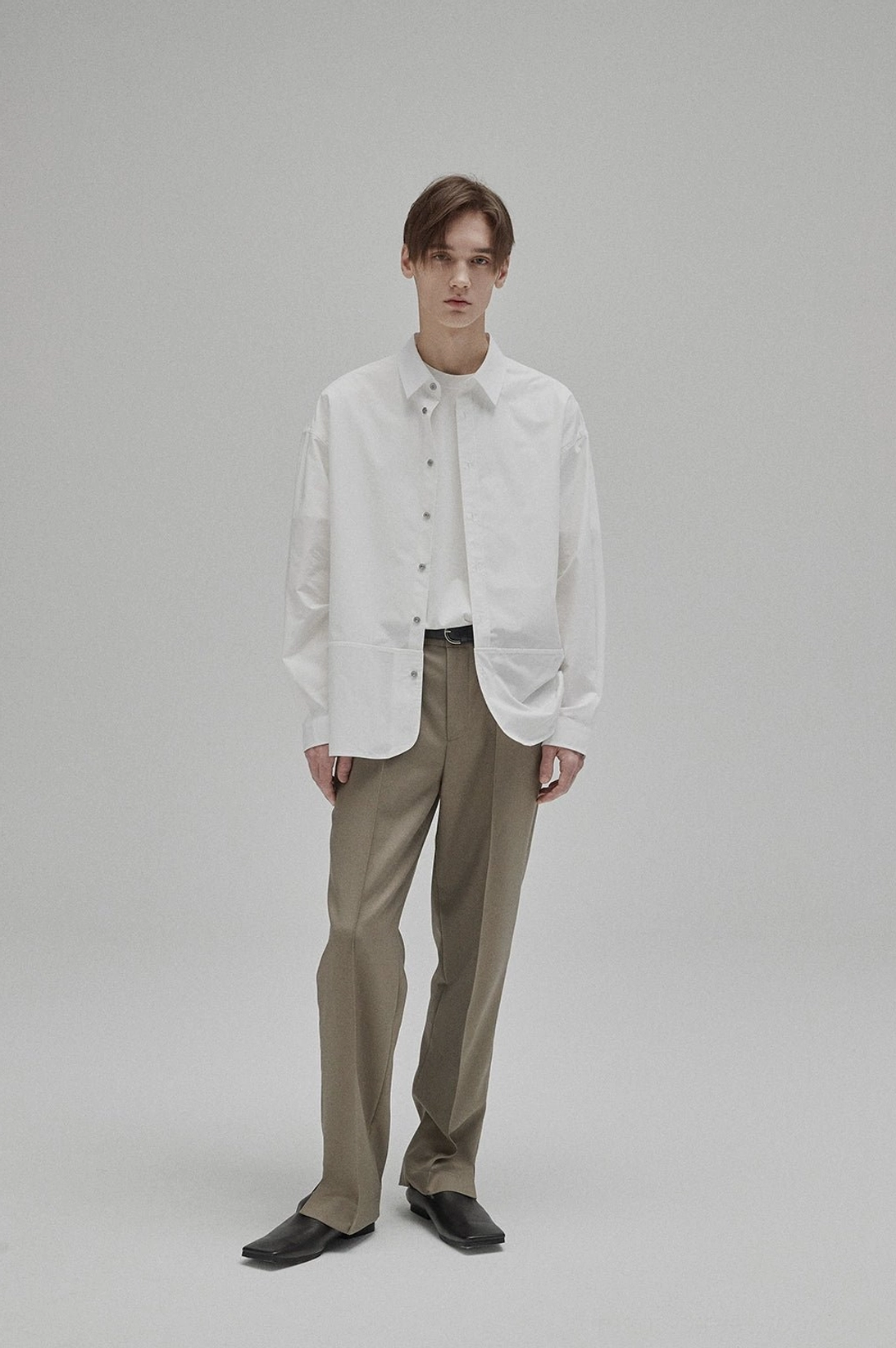 White cotton crew neck base layer styled under a crisp button-down shirt with khaki trousers and black loafers