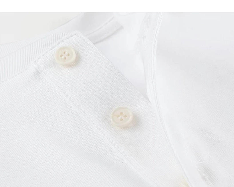 Close-up of off-white buttons and neatly stitched placket on a soft white cotton Henley streetwear T-shirt