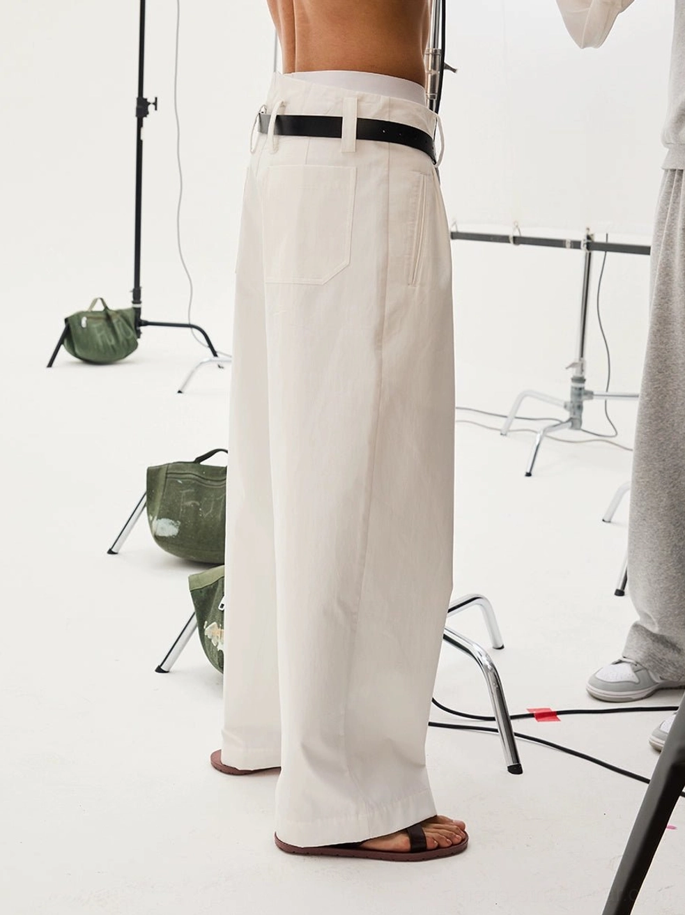 Close-up back view of white cotton twill tailored wide-leg trousers showing the V-notch waistband, back patch pocket, and sturdy fabric