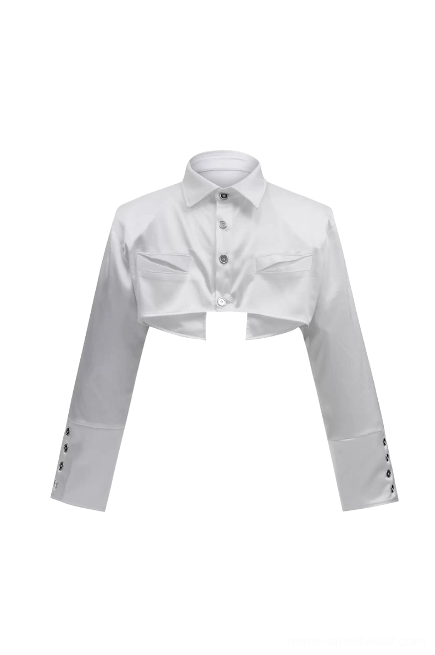 Flat lay white cropped button-down shirt with pointed collar, front metal buttons, chest patch pockets, and decorative cuff fasteners