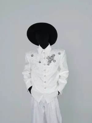 Front view of a white crystal embellished cropped jacket styled with matching wide leg trousers and a black western cowboy hat